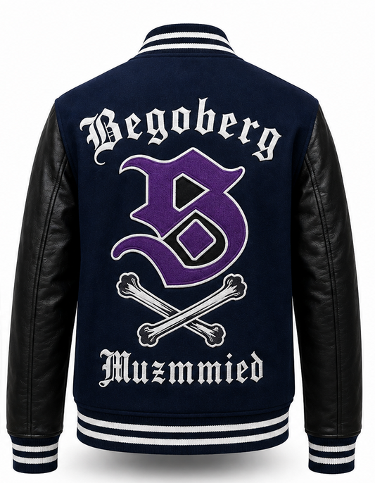 Back view of a varsity-style jacket with a navy blue body, black faux-leather sleeves, and white and purple embroidery reading 'Begoberg' and 'Muzmmied' with a large purple letter B and crossed bones.