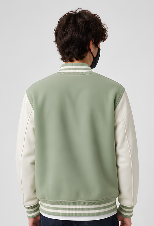 Person wearing a mint green and white varsity jacket on a plain background