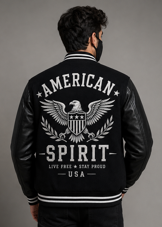 A man viewed from the back wearing a black leather and fleece varsity-style jacket with a large white logo on the back reading 'AMERICAN SPIRIT' and 'LIVE FREE * STAY PROUD * USA'.