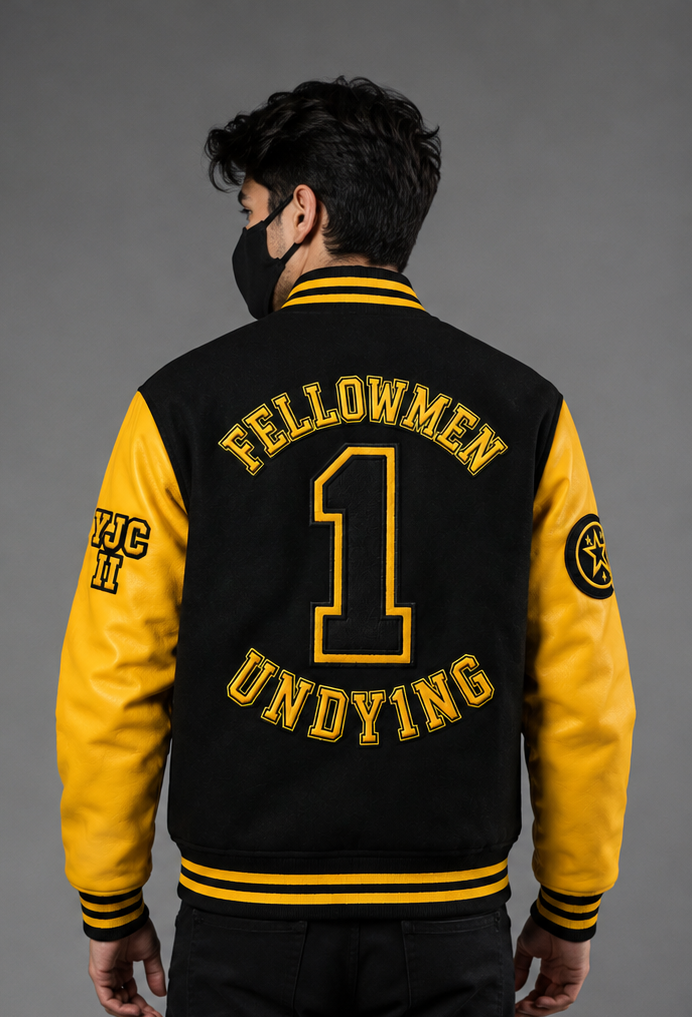 A man viewed from the back wearing a varsity-style jacket with yellow sleeves and black body, featuring yellow embroidered text reading 'FELLOWMEN UNDYING' and a large number 1 on the back.