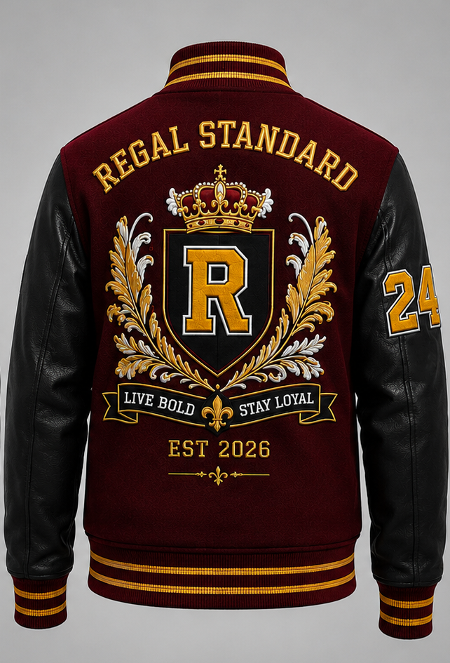A maroon and black varsity-style jacket shown from the back, featuring a large gold, black, and white crest with the letter R, the words 'REGAL STANDARD' across the shoulders, and 'LIVE BOLD STAY LOYAL EST 2026' on a ribbon. The sleeves are black with gold and white numbering.