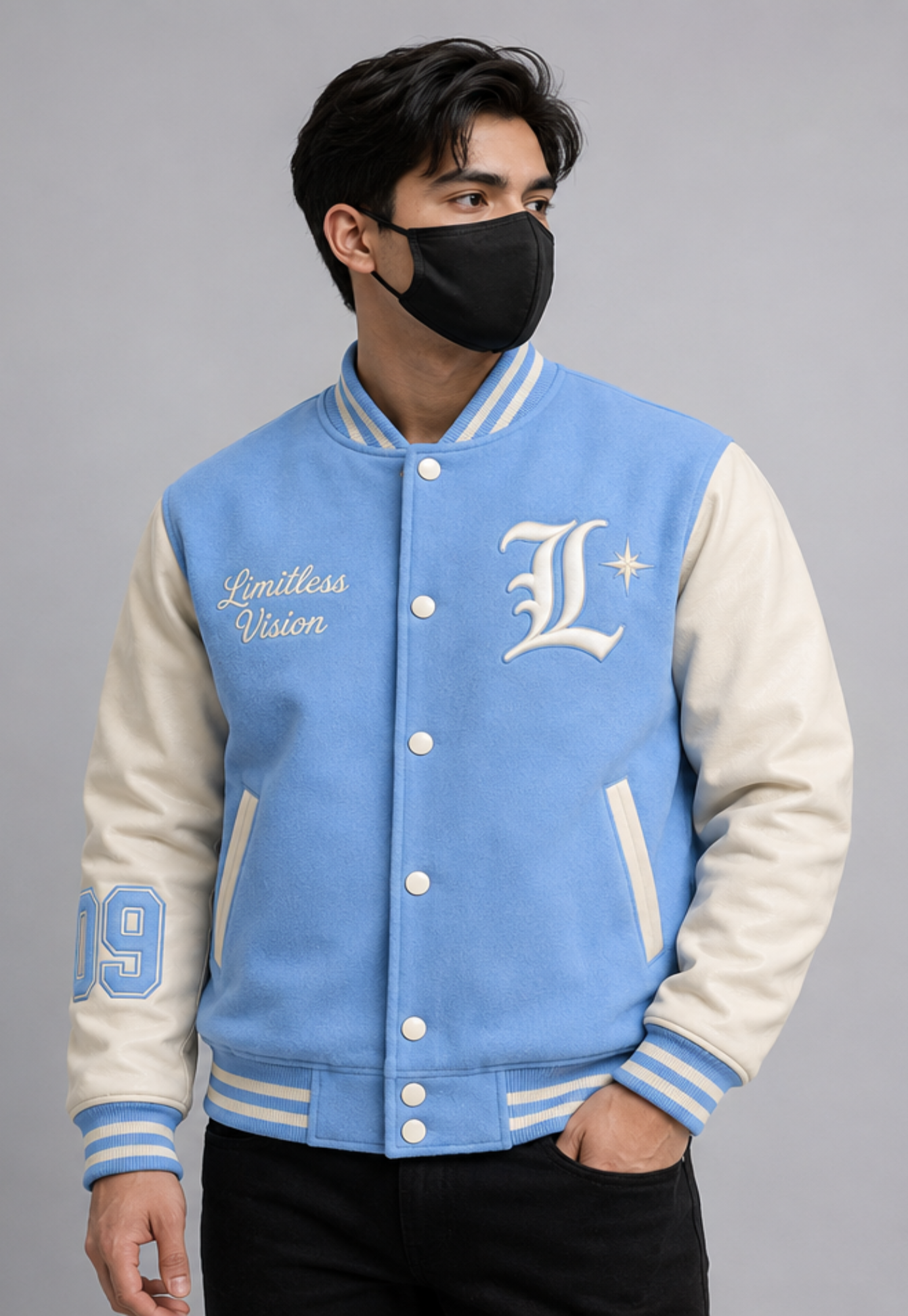 A man wearing a sky blue and white varsity jacket with white buttons, featuring 'Limitless Vision' and a large 'L' logo on the chest, posed against a solid gray background.
