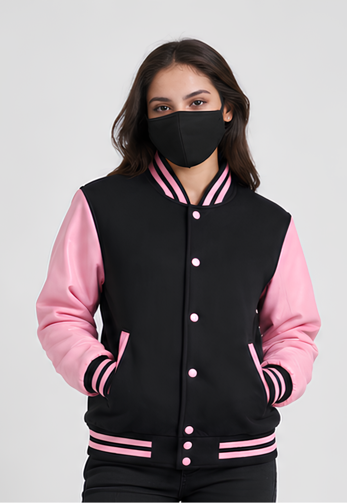 Person wearing a black and pink varsity jacket with a face mask on a light gray background