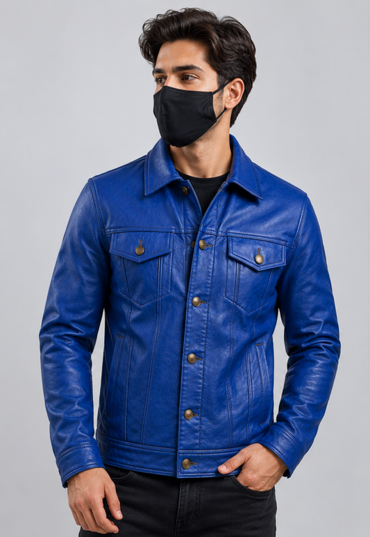 A man wearing a vibrant blue leather trucker jacket over a black shirt and black pants, wearing a black face mask. The photo is taken against a solid light gray background.