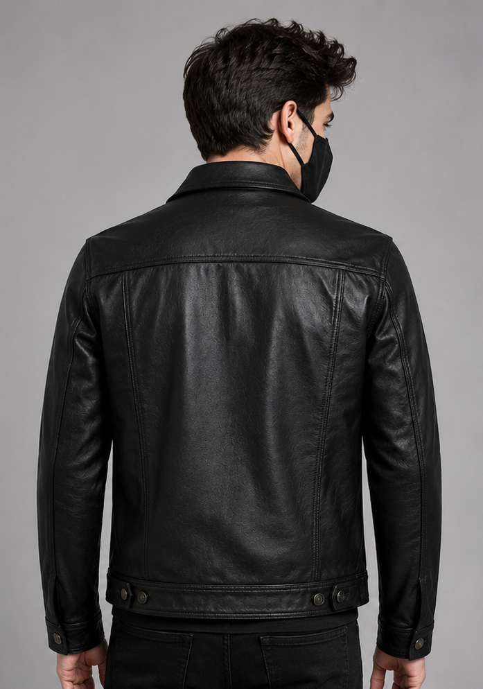 A man viewed from the back wearing a black leather jacket and a black face mask, set against a solid gray studio background.