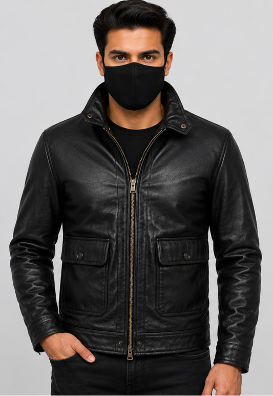 A man wearing a black leather jacket with a front zipper, snap-button collar, and flap pockets, paired with a black face mask and black shirt, against a solid gray background.