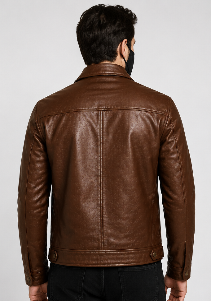 A man viewed from the back wearing a brown leather jacket, black pants, and a black face mask, against a light gray studio background.