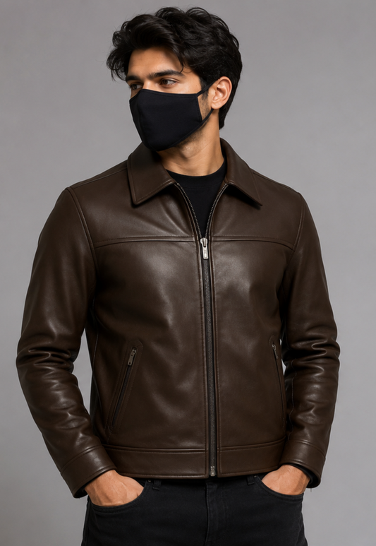 A man wearing a dark brown leather jacket with a black face mask, photographed against a plain gray studio background.