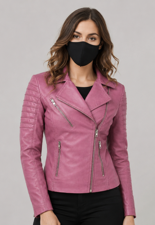 A woman wearing a pink leather moto jacket with silver zippers, styled with a black face mask and black pants, against a solid gray studio background.