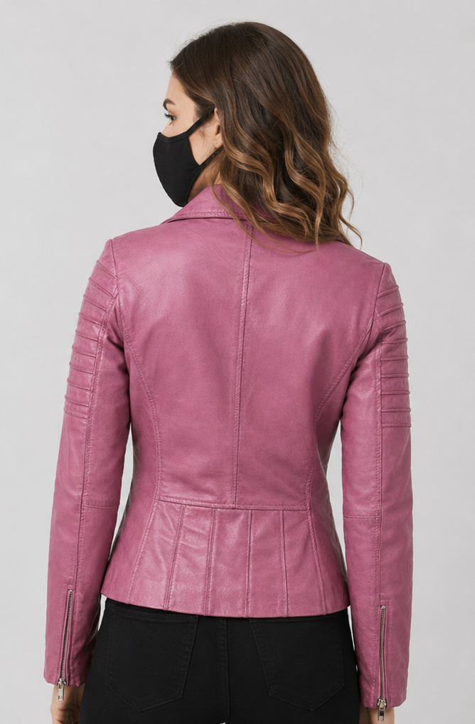 A woman shown from the back wearing a fitted pink leather moto jacket with zippered sleeve details and a peplum-like waist seam, paired with black pants against a light gray studio background.