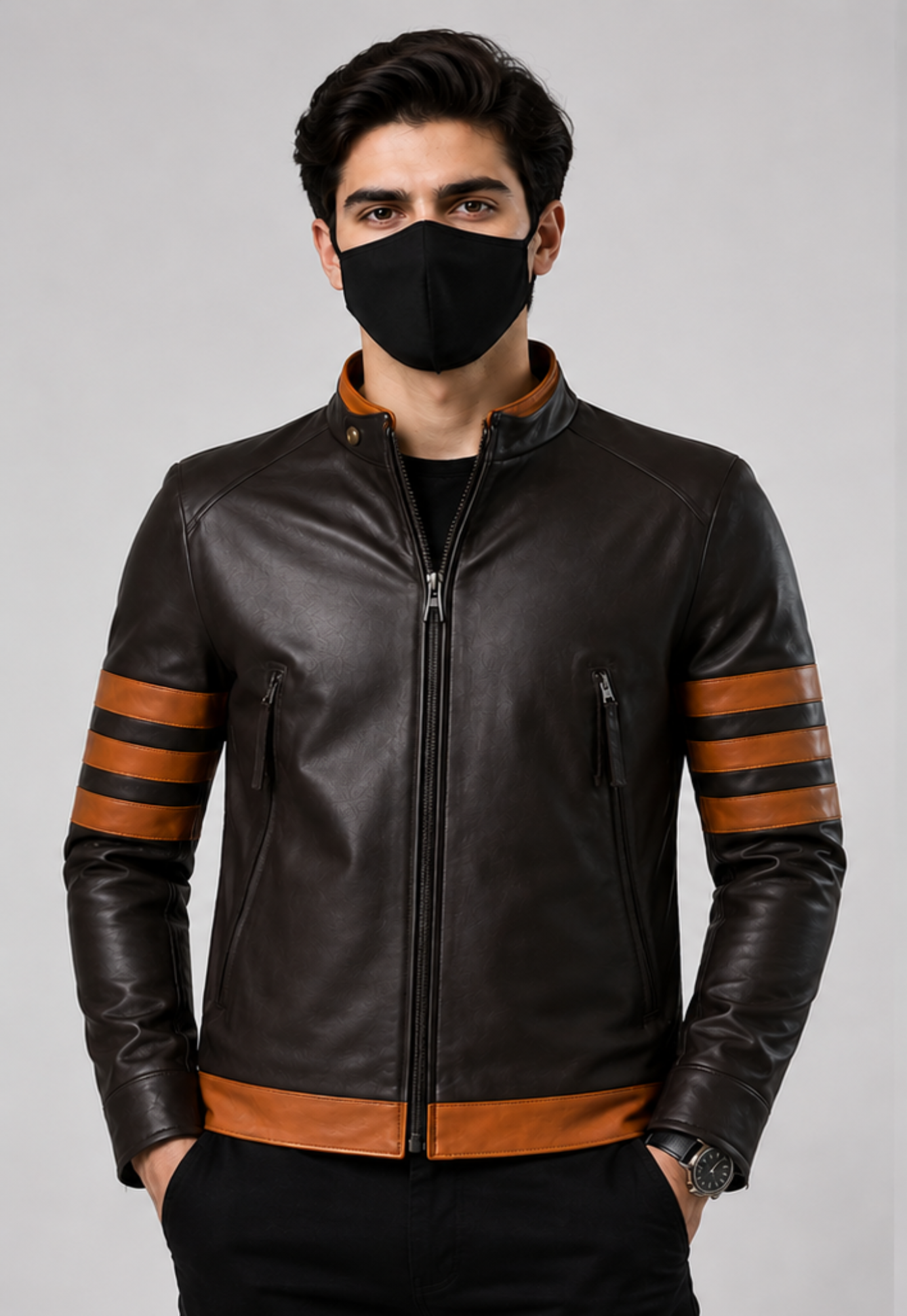 A man wearing a dark brown leather jacket with brown stripe accents on the sleeves and hem, paired with a black face mask and black pants, against a plain gray studio background.
