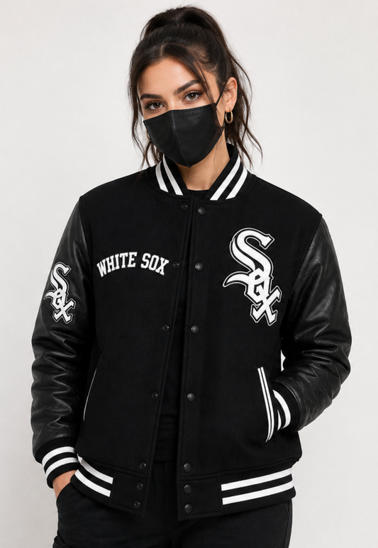 A woman wearing a black varsity jacket with white embroidered details. The jacket features 'WHITE SOX' text on the right chest and a large 'Sox' logo on the left chest, with matching sleeve embroidery.