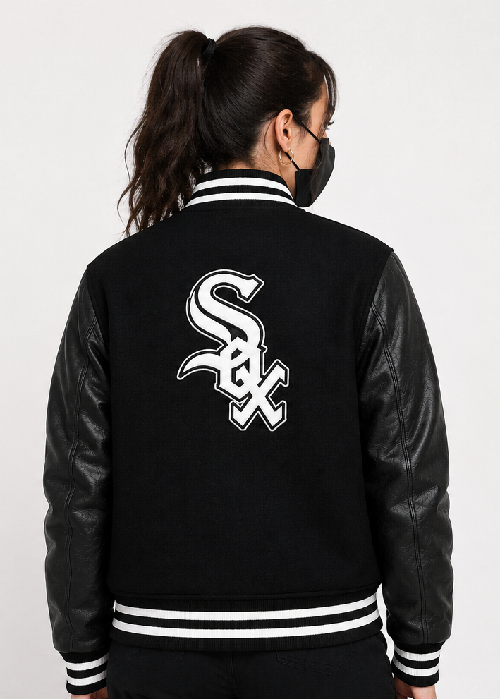 A person shown from the back wearing a black varsity-style jacket with black leather sleeves, white striped ribbing, and a large white Chicago White Sox 'SOX' logo on the back, against a plain light background.