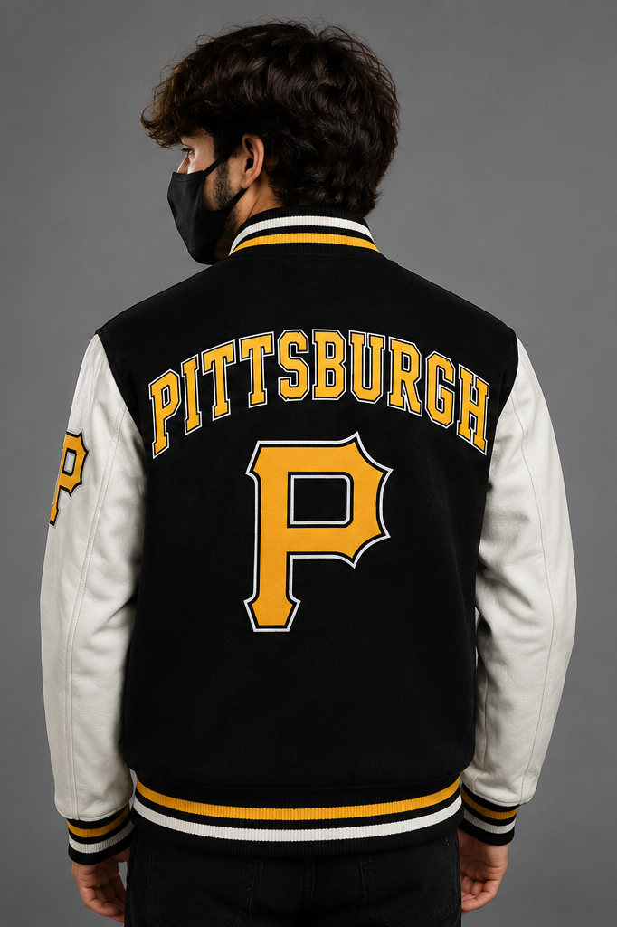 A man viewed from the back wearing a black and white varsity jacket with 'PITTSBURGH' and a large 'P' embroidered on the back, set against a solid gray studio background.