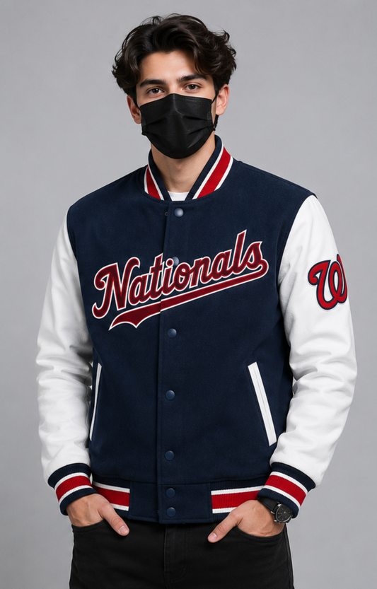 A man wearing a navy and white varsity jacket with 'Nationals' written in red script across the chest, posed against a solid gray studio background.
