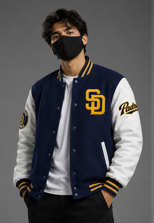 A man wearing a navy and white varsity jacket with yellow accents, featuring the San Diego Padres 'SD' logo on the chest and 'Padres' script on the sleeve, over a white t-shirt and black pants.