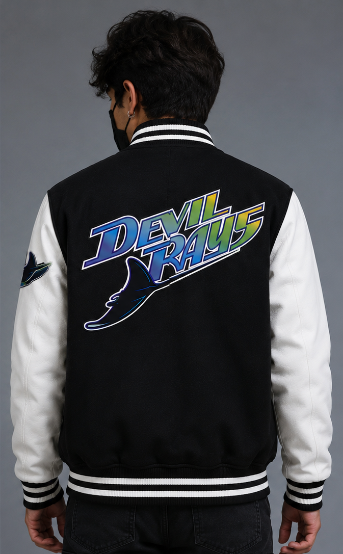 A man viewed from behind wearing a black-and-white varsity jacket with a large 'Devil Rays' graphic embroidery on the back in blue, green, and yellow.