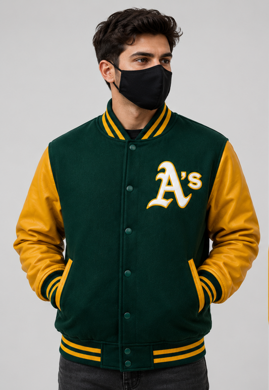 A man wearing a dark green and gold varsity jacket with an 'A's' logo on the chest, paired with a black face mask, set against a plain gray studio background.