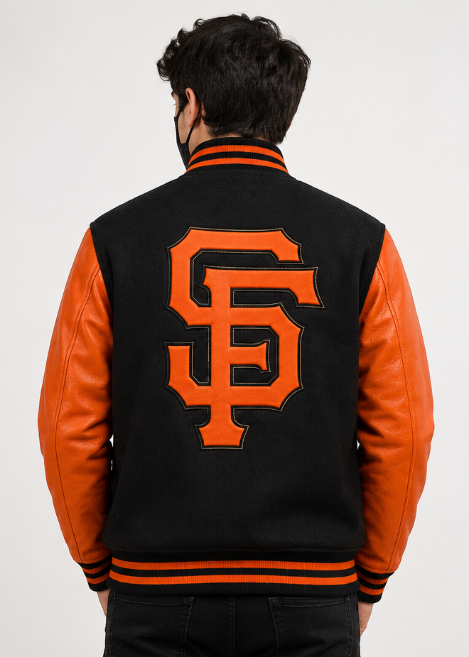 A man viewed from behind wearing a black and orange varsity jacket with a large orange 'SF' embroidery logo on the back, set against a plain light gray background.