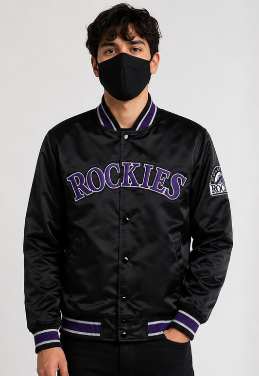 A man wearing a black satin varsity jacket with purple and white trim, featuring 'ROCKIES' in purple lettering across the chest, posed against a light gray background.