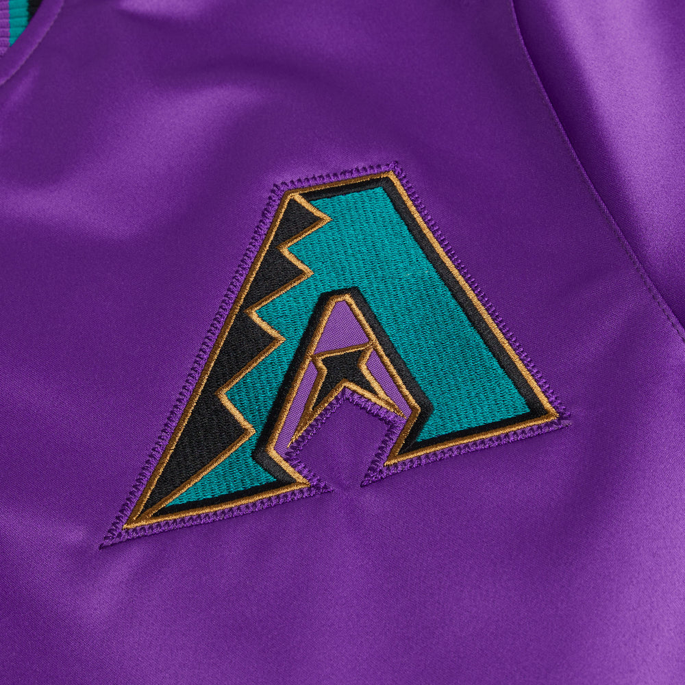Close-up of a purple fabric with a geometric logo featuring teal, black, and gold colors.