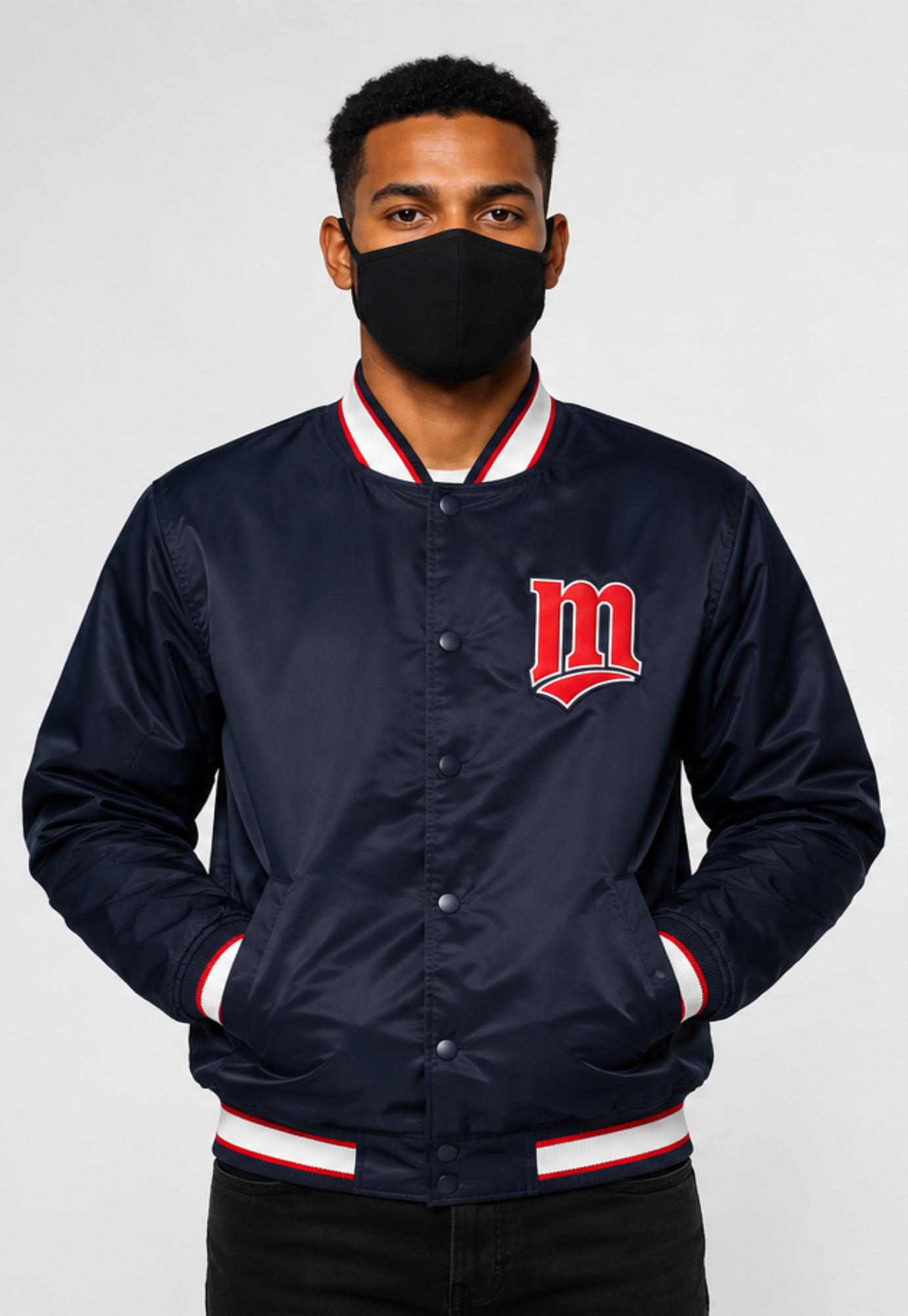 A man wearing an MLB Minnesota Twins navy blue satin varsity jacket with red and white ribbed trim, featuring a red embroidered letter 'M' on the chest, posed against a light gray background.