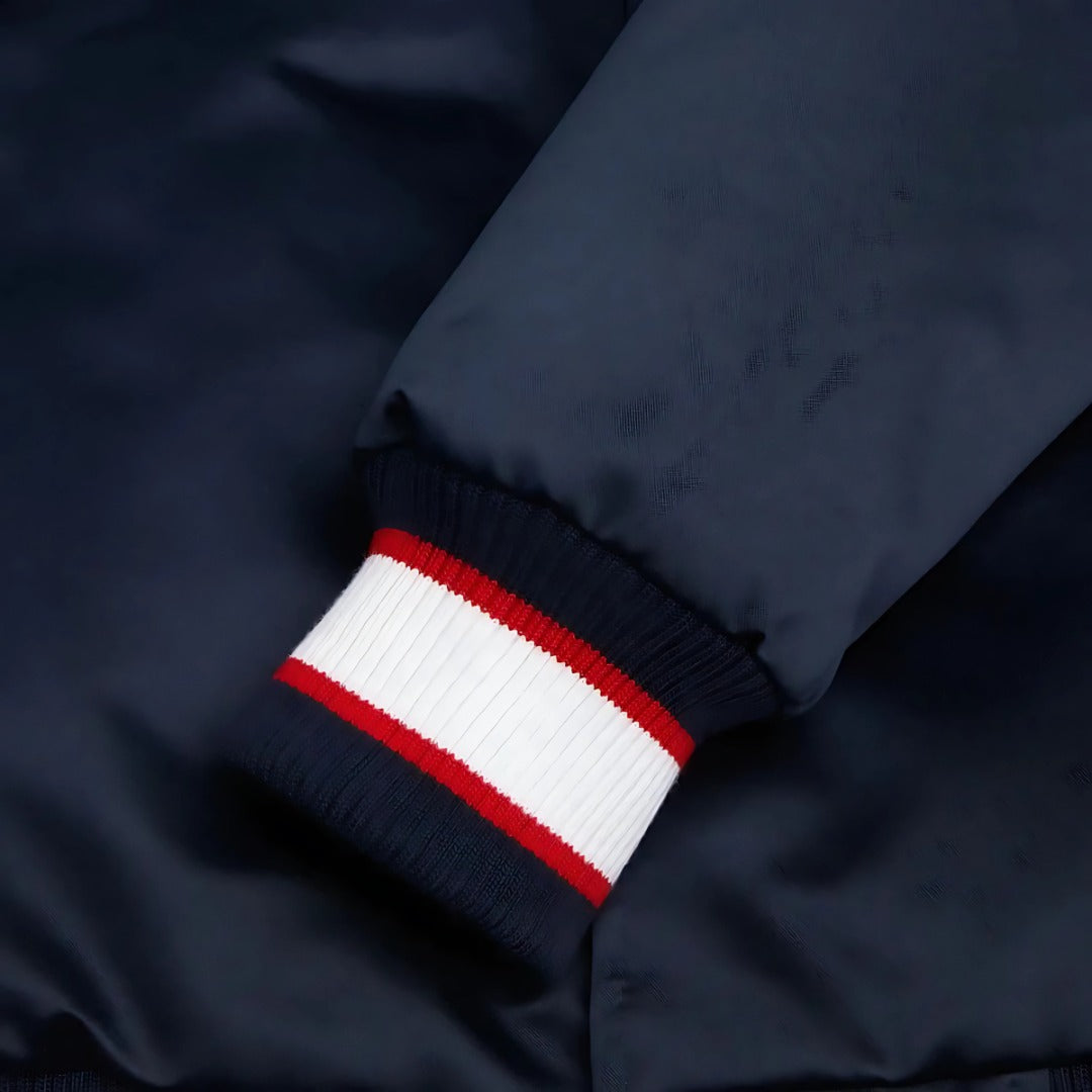 Close-up of a navy blue jacket with a red and white striped cuff.