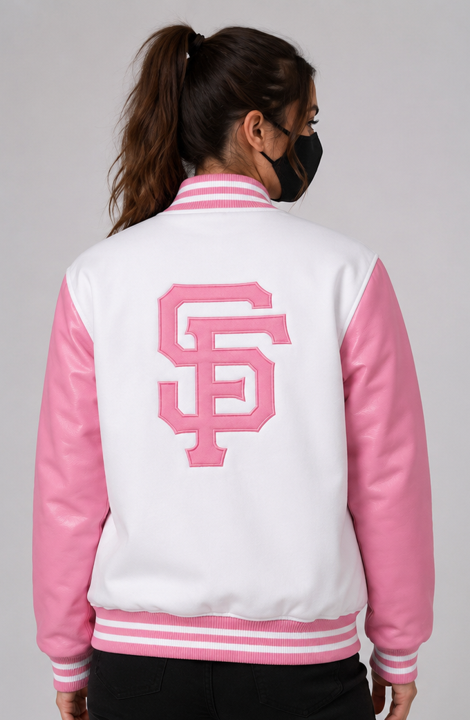 A woman shown from the back wearing a varsity-style jacket with a white body, pink sleeves, and a large pink embroidered 'SF' logo on the back, photographed against a light gray studio background.