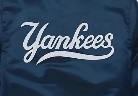 Close-up of a navy blue jacket or fabric panel with a large white cursive 'Yankees' logo across the front.