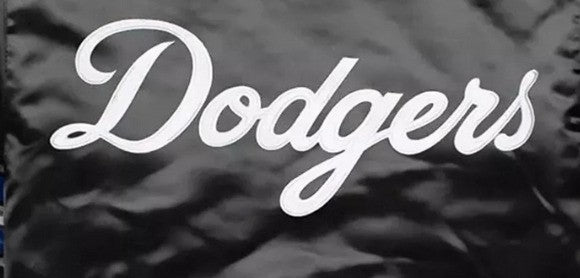 A close-up of a black fabric surface with the word 'Dodgers' in large white cursive script across the center.