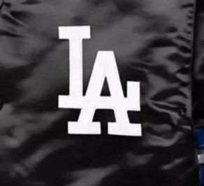 Close-up of a black satin or shiny fabric surface with a large white interlocking LA logo centered on it.