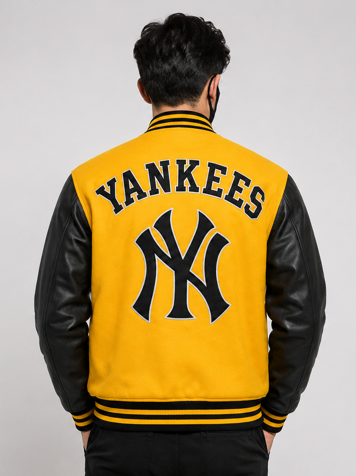 A man viewed from behind wearing a yellow and black varsity jacket with 'YANKEES' and the New York Yankees logo embroidered on the back.