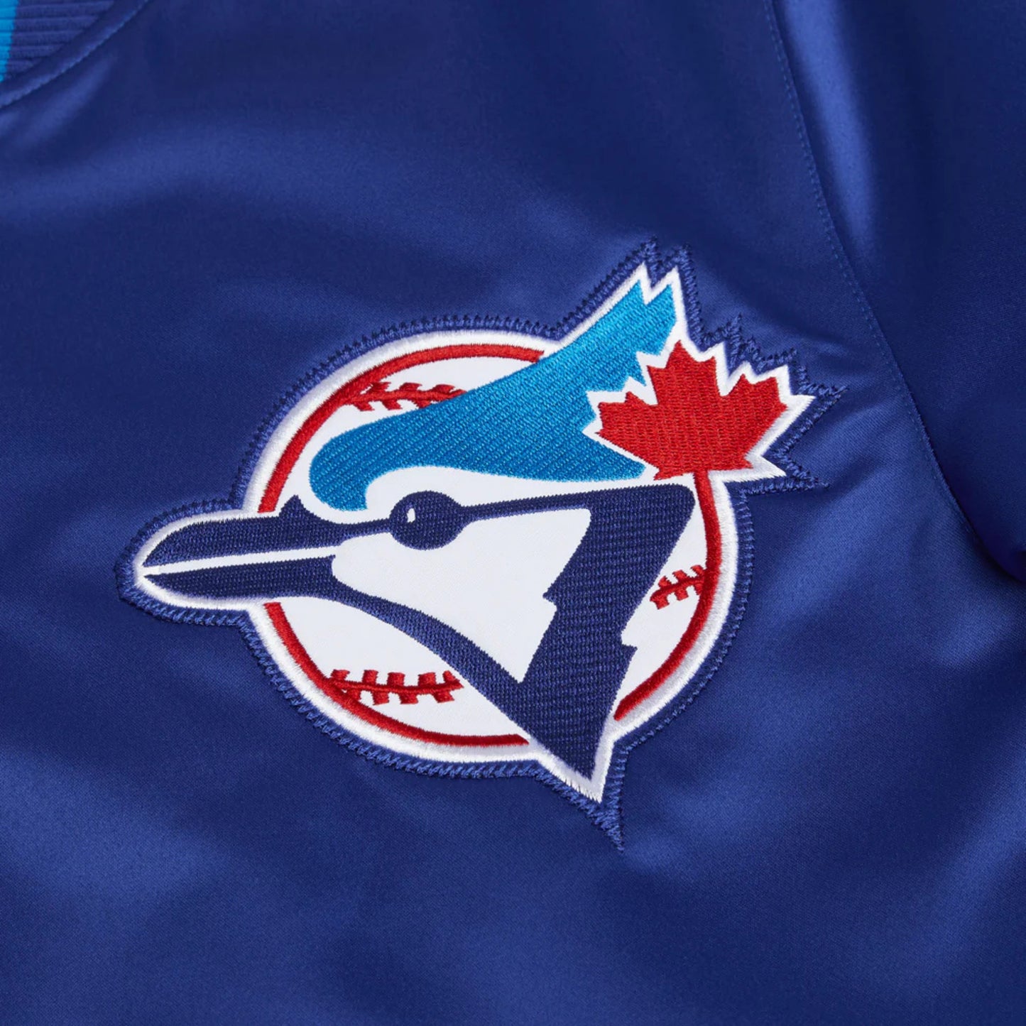Close-up of a blue sports jersey with a logo featuring a blue bird, red maple leaf, and white baseball.