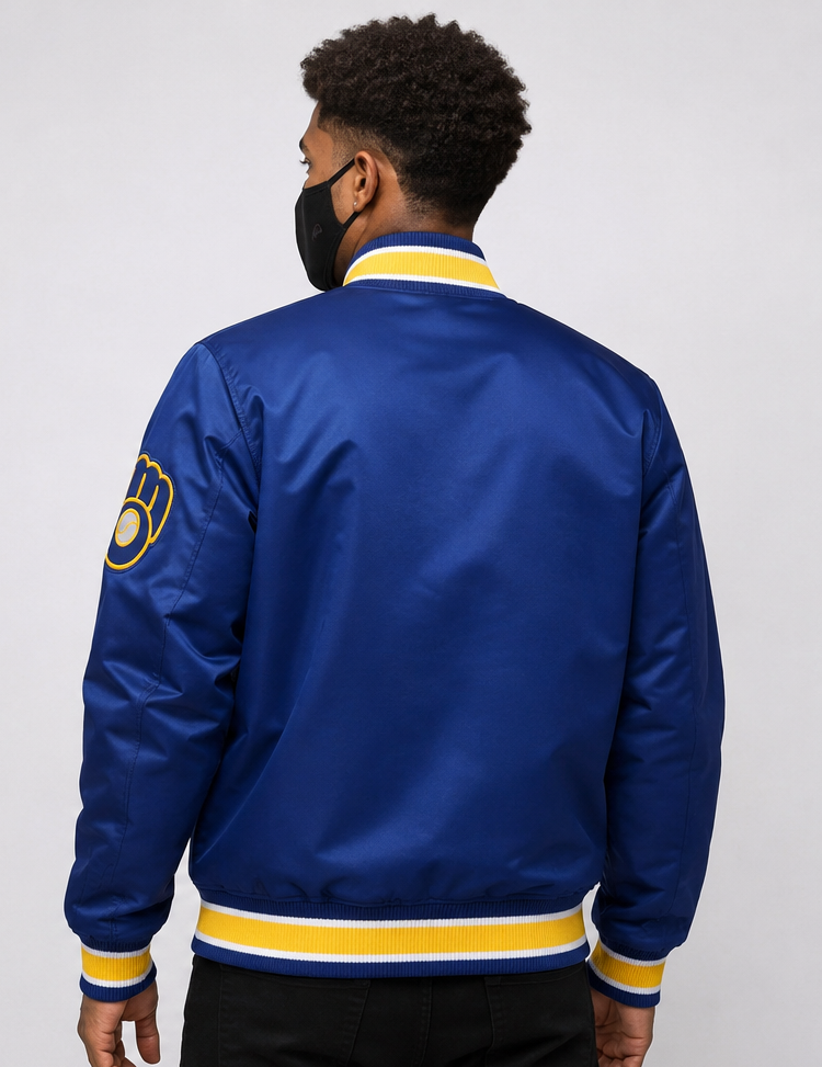 A man wearing a royal blue satin bomber jacket with yellow and white striped ribbing, shown from the back against a light gray studio background.