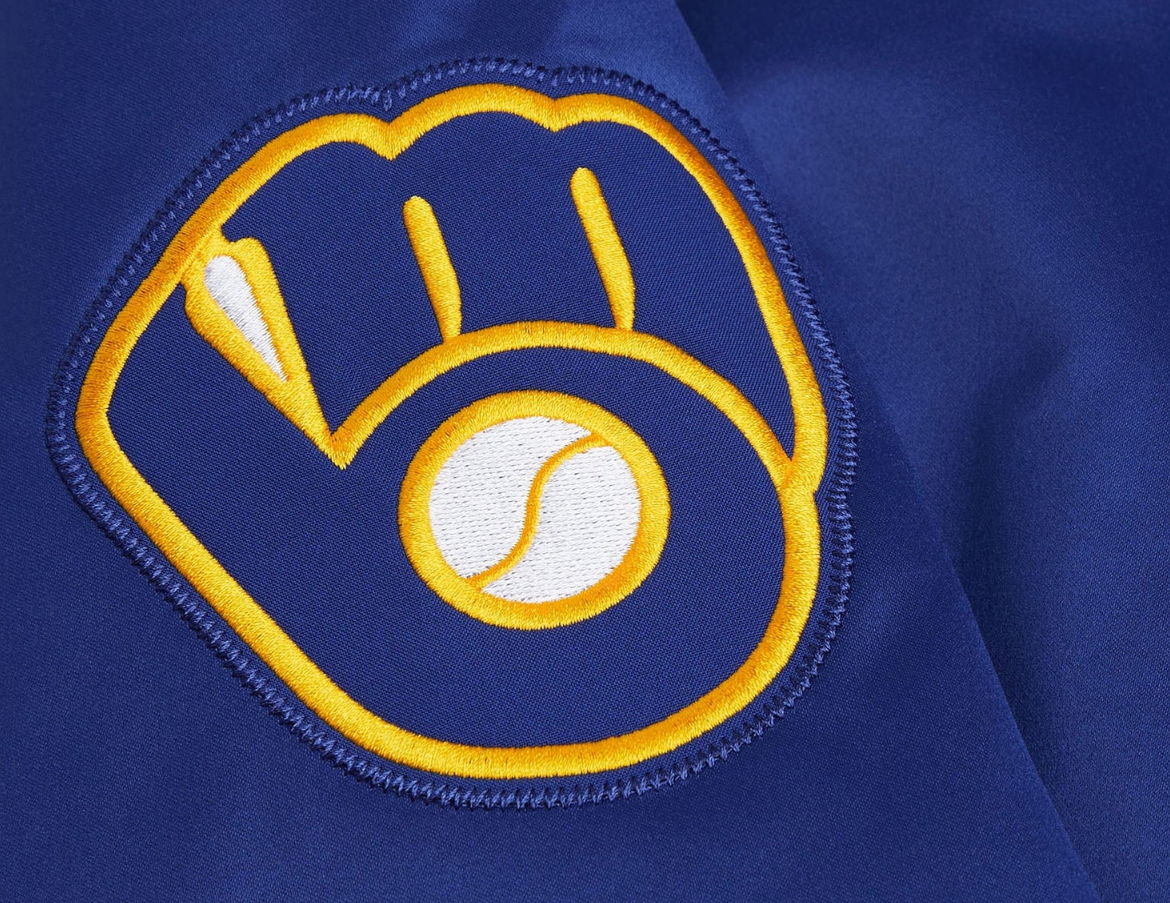 Close-up of a royal blue embroidered baseball jacket featuring a glove with a baseball logo patch on the sleeve.