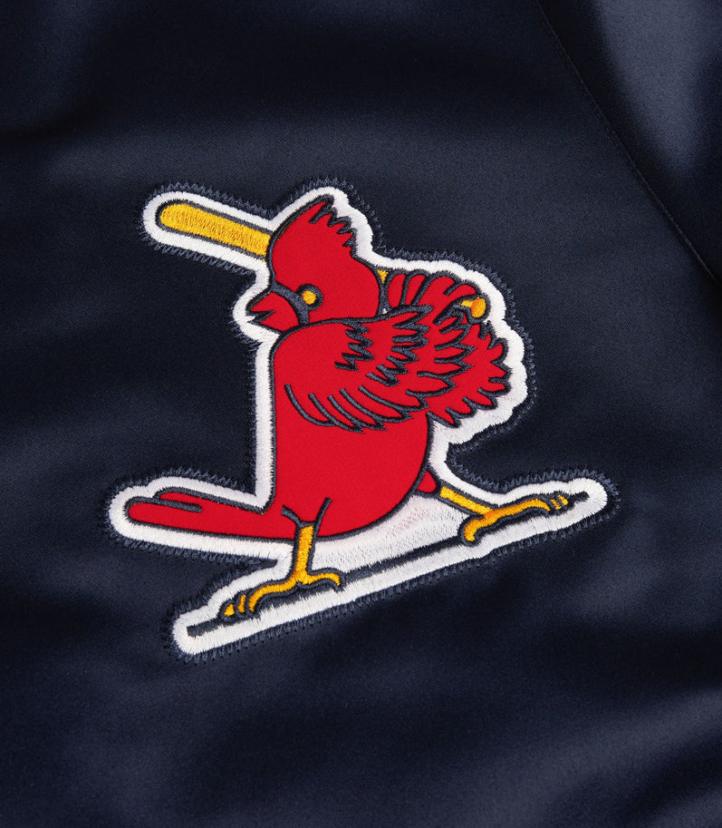 Close-up of a red cardinal embroidered patch with a yellow bat and white outline on a dark navy fabric background.