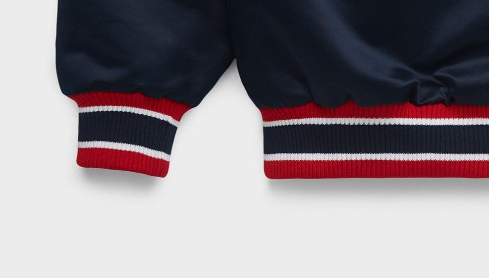 Close-up of navy blue ribbed knit cuffs with red and white stripes, shown on a light gray background.