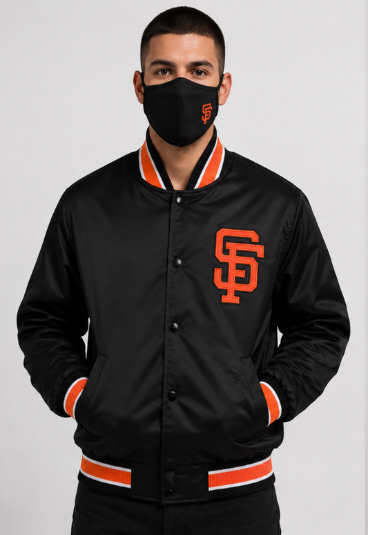 A man wearing a dark brown San Francisco Giants varsity jacket with orange and white ribbed trim, paired with a black face mask featuring the San Francisco Giants logo, against a light gray studio background.