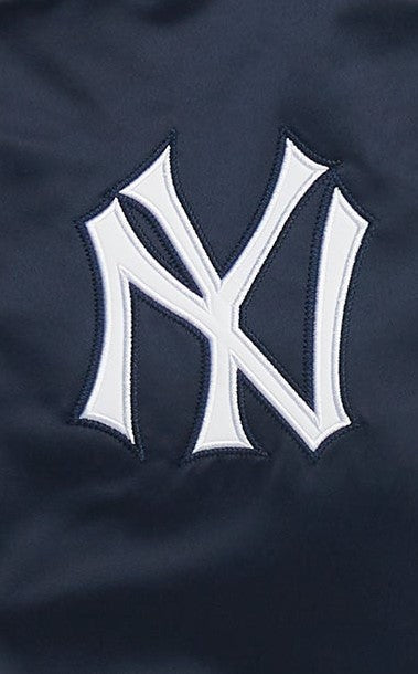 Close-up of a navy blue fabric with a large white embroidered New York Yankees 'NY' logo.