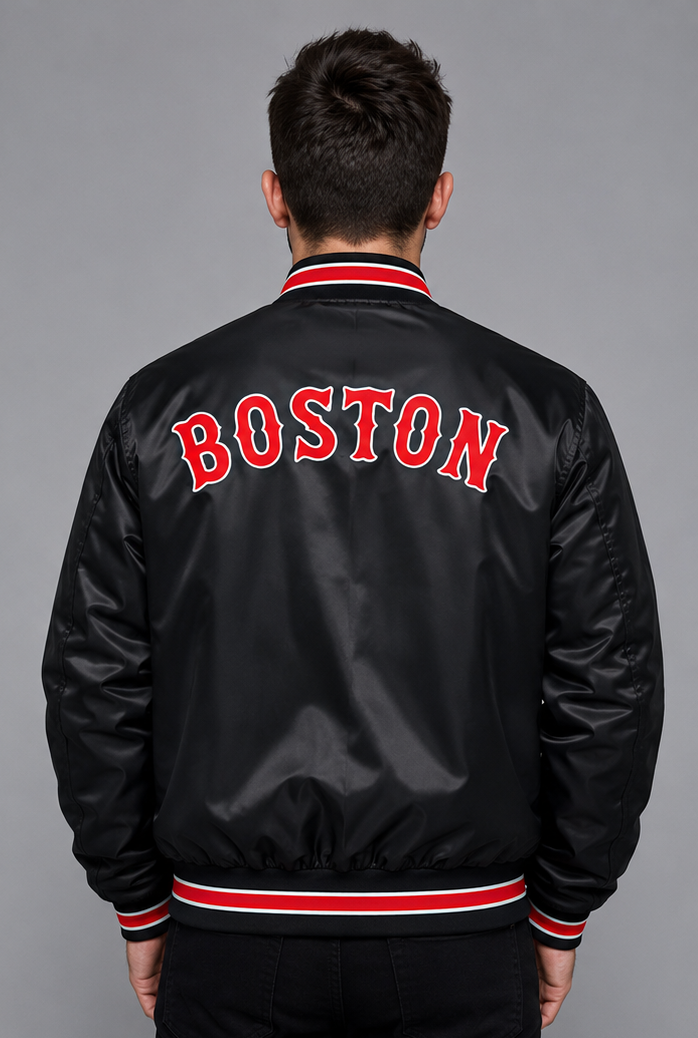A man viewed from behind wearing a black satin bomber jacket with 'BOSTON' embroidered in red across the back, featuring red and white striped ribbing on the collar, cuffs, and hem.