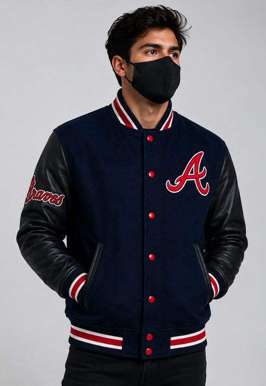 A man wearing a navy blue and black varsity jacket with red and white trim, featuring the Atlanta Braves 'A' logo on the chest, posed against a solid gray background.