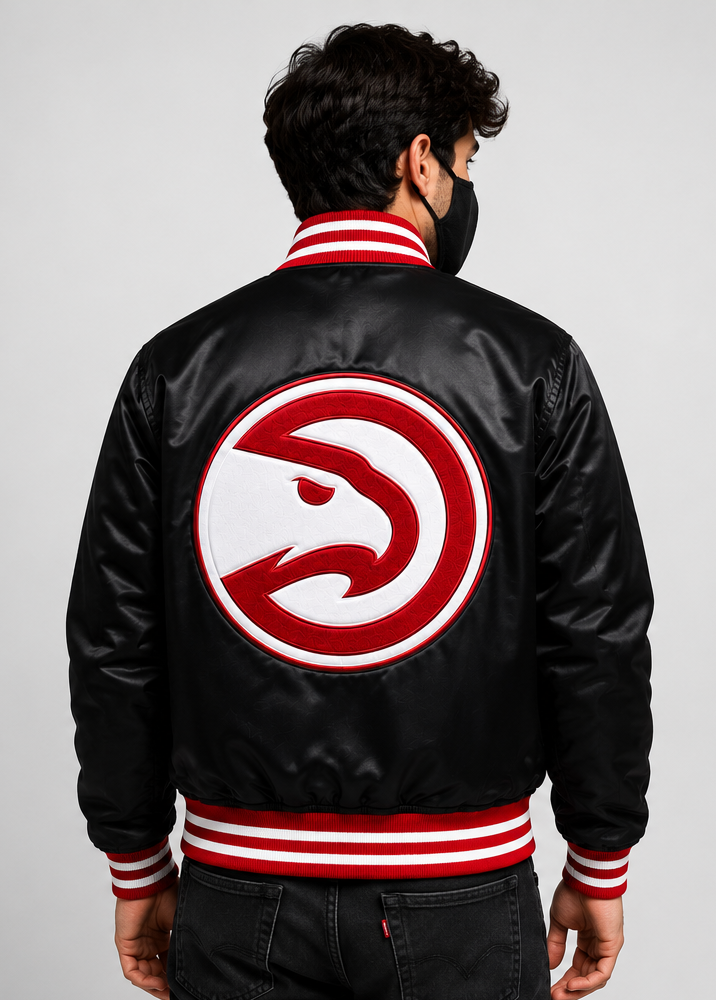 A man viewed from behind wearing a black satin varsity-style bomber jacket with red and white striped ribbed collar, cuffs, and hem, featuring a large red and white eagle logo patch on the back.