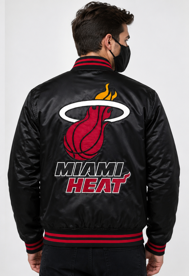 A man viewed from the back wearing a black Miami Heat satin bomber jacket with red and white ribbed trim and a large Miami Heat logo on the back.