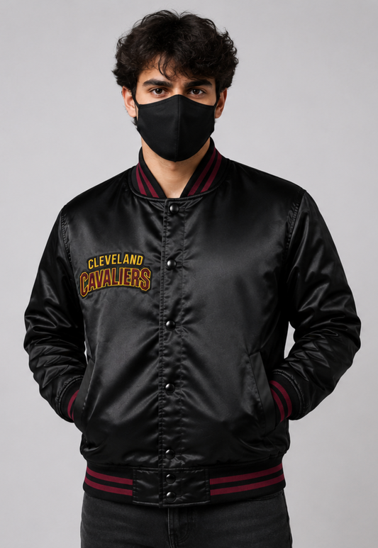 A man wearing a black satin Cleveland Cavaliers varsity jacket with dark red ribbed trim and a black face mask, photographed against a neutral gray background.