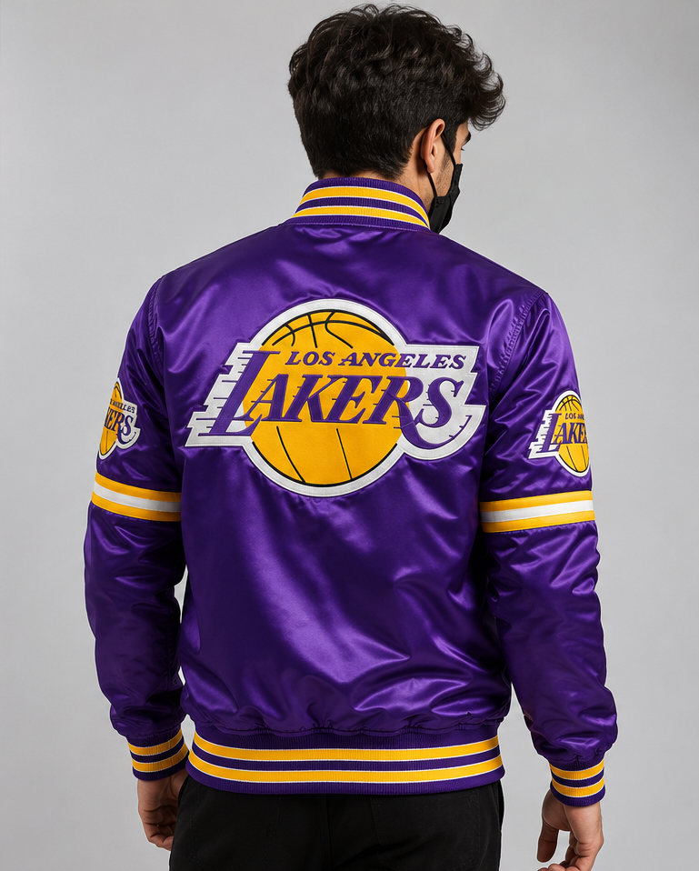 A man viewed from behind wearing a purple Los Angeles Lakers satin bomber jacket with yellow and white stripes and a large Lakers logo on the back.
