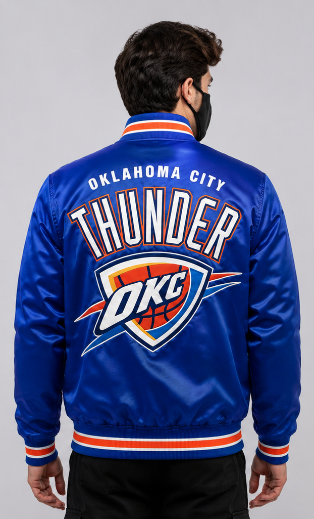 A man viewed from the back wearing a royal blue satin Oklahoma City Thunder varsity jacket with large white, orange, and blue team graphics on the back.