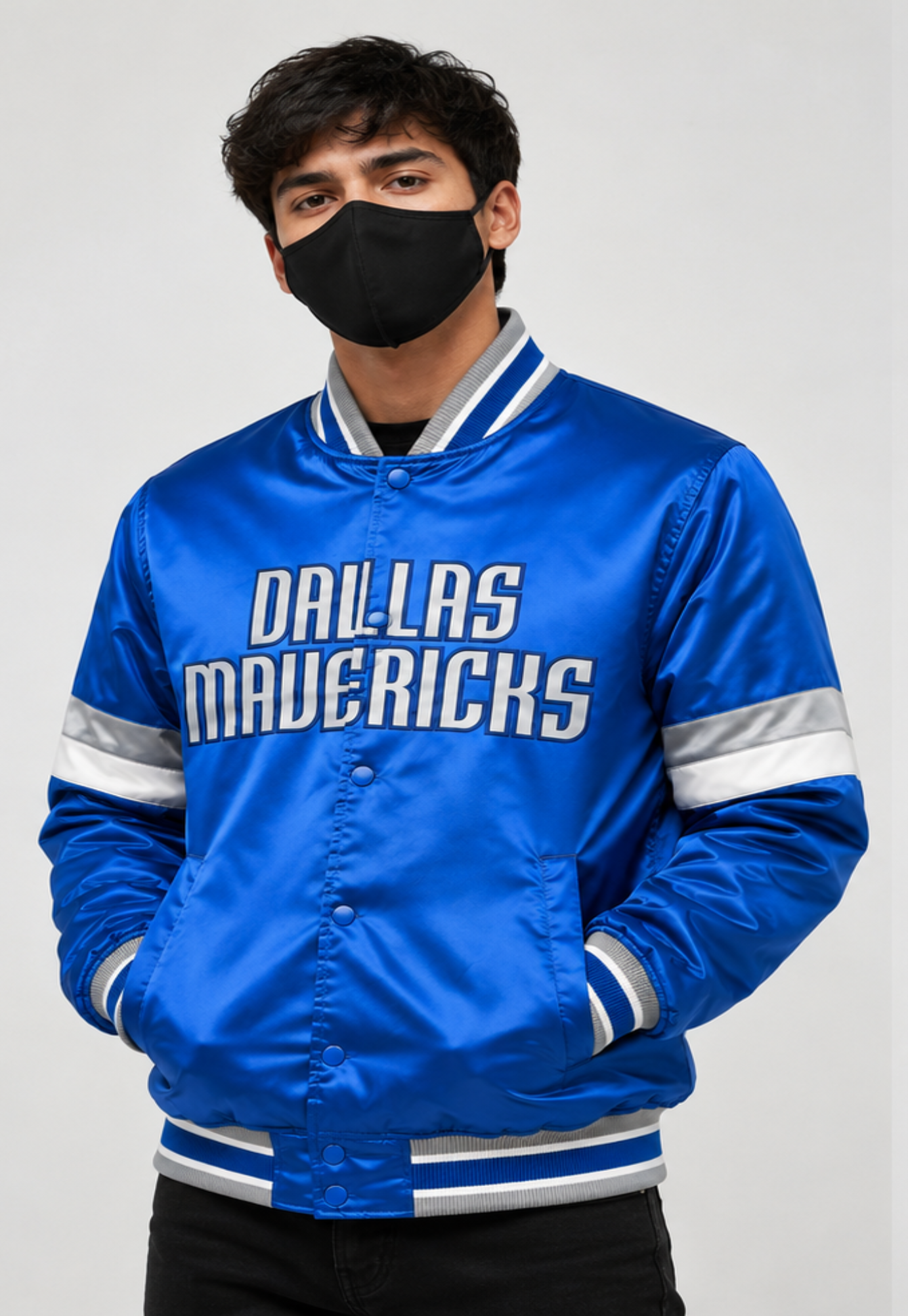 A man wearing a bright blue satin Dallas Mavericks varsity jacket with white and gray stripes, posing against a light gray background.