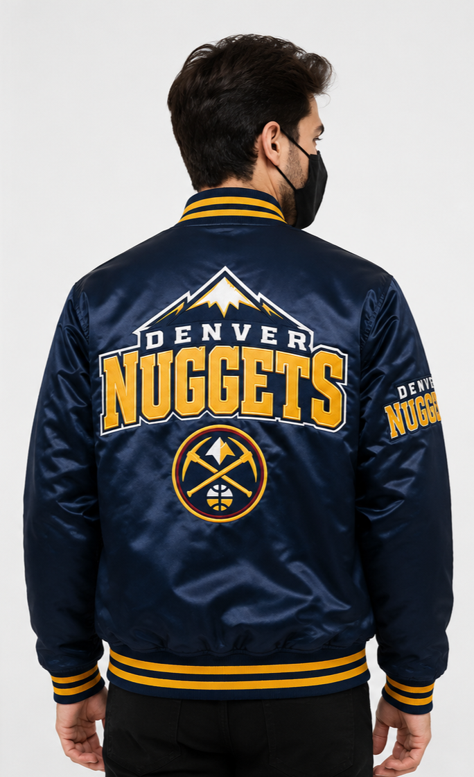 A man viewed from the back wearing a navy blue Denver Nuggets satin bomber jacket with yellow and white graphics, including the team logo and 'DENVER NUGGETS' text.