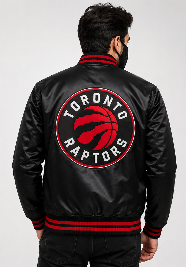 A man viewed from behind wearing a black satin bomber jacket with a large red and white Toronto Raptors logo on the back, featuring red and black striped ribbed collar, cuffs, and hem.