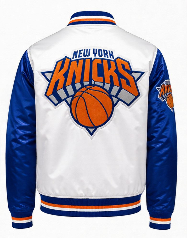 White and blue New York Knicks satin jacket shown from the back, featuring a large Knicks logo and basketball graphic on the back, with blue sleeves and striped ribbed collar, cuffs, and hem.